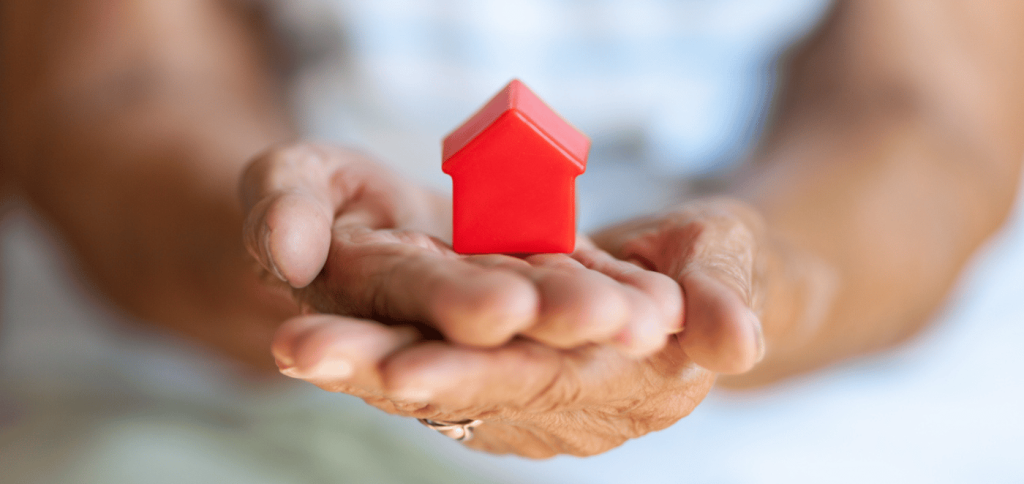 Hands holding a plastic red house